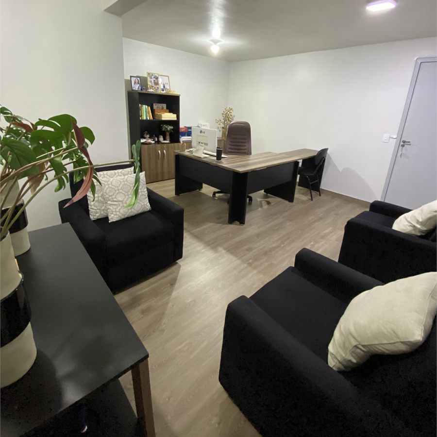 Sala de atendimento com poltronas e mesa de trabalho